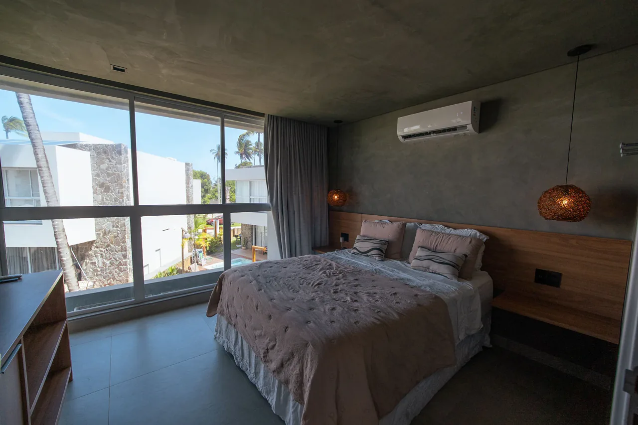 Suíte da Morada de Charme com ampla janela e vista para o condomínio